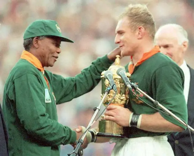 South African President Nelson Mandela (L) congratulates Springbok skipper Francois Pienaar after handing him the William Webb Ellis trophy at Ellis Park in Johannesburg 24 June