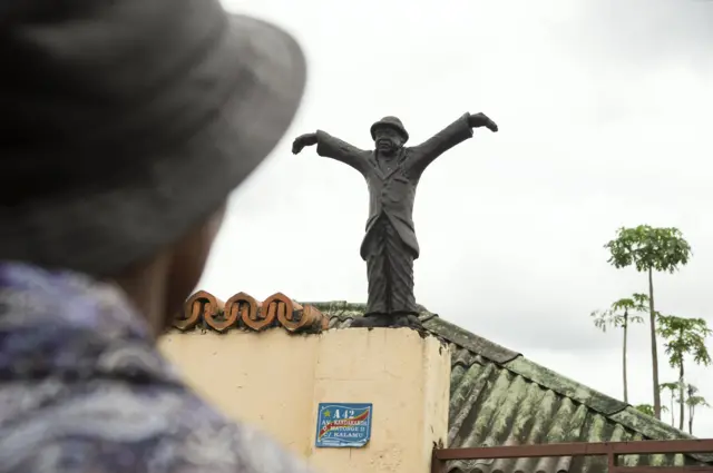 People stand in front of the childhood house of Congolese world music legend, renowned as the "king of Congolese rumba", Papa Wemba, in the district of Matonge, in Kinshasa, on April 25, 2016. Papa Wemba, one of Africa"s greatest music stars, died on April 24 after collapsing on stage during a festival in Ivory Coast. The Congolese world music legend, renowned as the "king of Congolese rumba" for the fusion of Cuban and electronic rock that he pioneered in the 1970s, was 66.