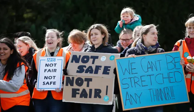 Demonstrators and junior doctors hold placards as they protest outside the Basingstoke and North Hampshire Hospital, in Basingstoke,