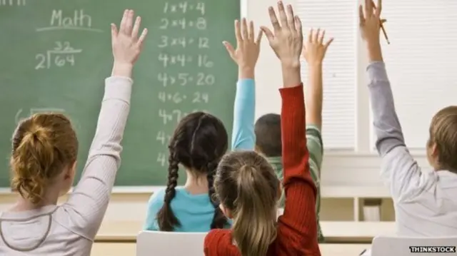 Pupils raising their hands in the classroom