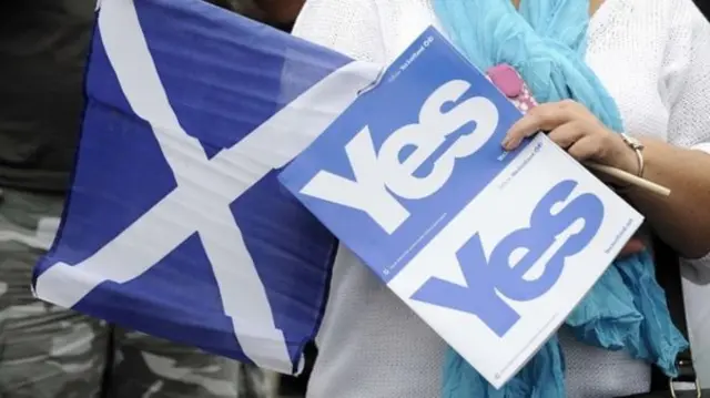 Voter holding 'yes' cards and Saltire