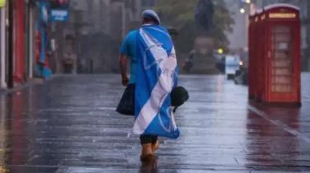 Man walking down street with yes flag on his back