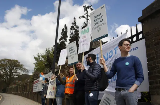 Junior doctors hold placards during a strike outside Chase Farm Hospital in London