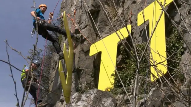 Rock climber installs letters on cliffs at Settle