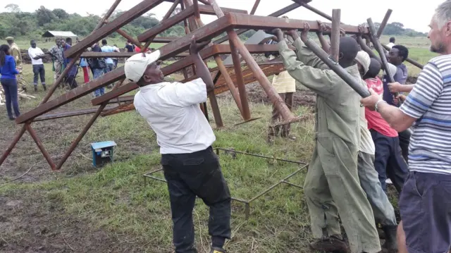 Men moving metalwork structure for ivory pyre