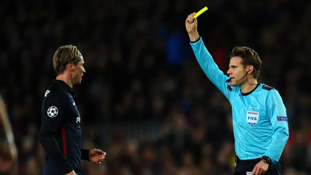 Fernando Torres of Atletico Madrid is shown a yellow card