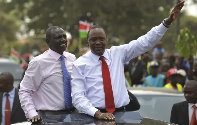 Kenya's president Uhuru Kenyatta (R) waves to the welcoming crowd flanked by deputy-president William Ruto on October 9, 2014 in Nairobi, a day after becoming the first sitting president to appear before the International Criminal Court on crimes against humanity charges