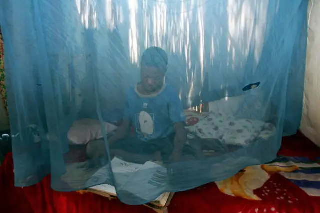 A child sits 22 June 2005 under a mosquito net in his home in the town Xai Xai, 200 kms north of Maputo