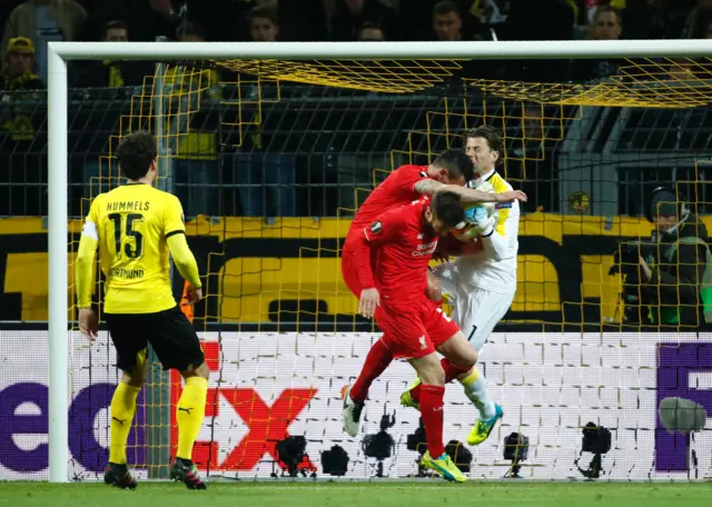 Dejan Lovren heads at goal as he collides with Roman Weidenfeller