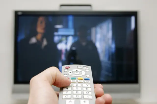 Person holding remote up to television.
