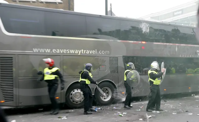 The Manchester United coach is pelted with beer bottles