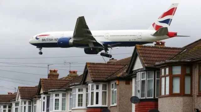 British Airways plane flying over homes