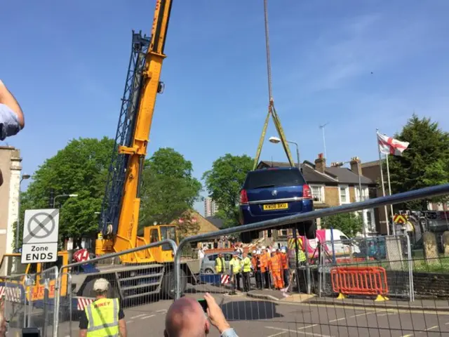 The crane lifts the car out of the hole