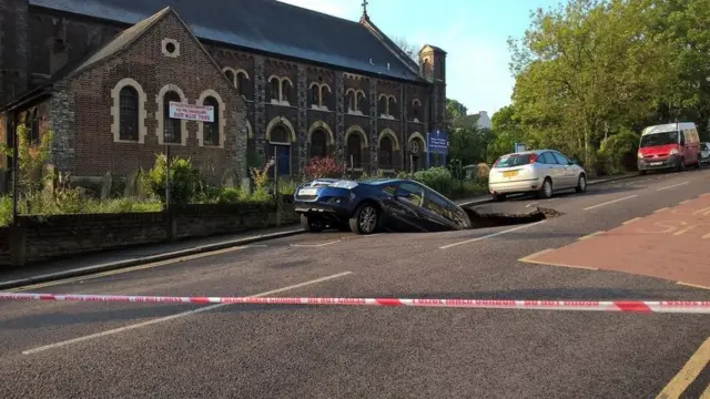 Car in sink hole outside church