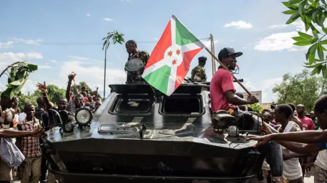 A man holding Burundi's flag stands on a tank as people celebrate in Bujumbura after the radio announcement that President Nkurunziza had been overthrown - 13 May 2015