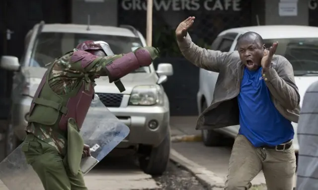 An opposition supporter yells out as he is beaten with a wooden club by riot police while trying to flee, during a protest in downtown Nairobi, Kenya Monday, May 16, 2016.