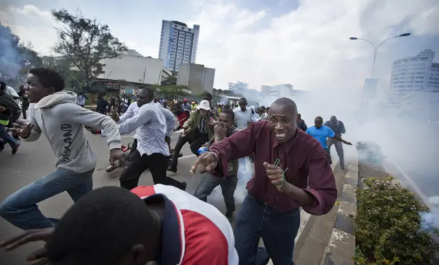 Opposition supporters, some carrying rocks, flee from clouds of tear gas fired by riot police, during a protest in downtown Nairobi, Kenya Monday, May 16, 2016.