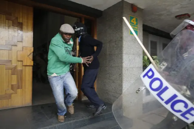 Man facing a police officer with a baton
