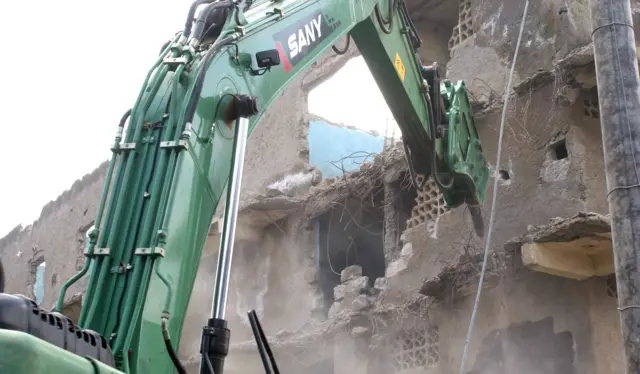 Digger destroying houses