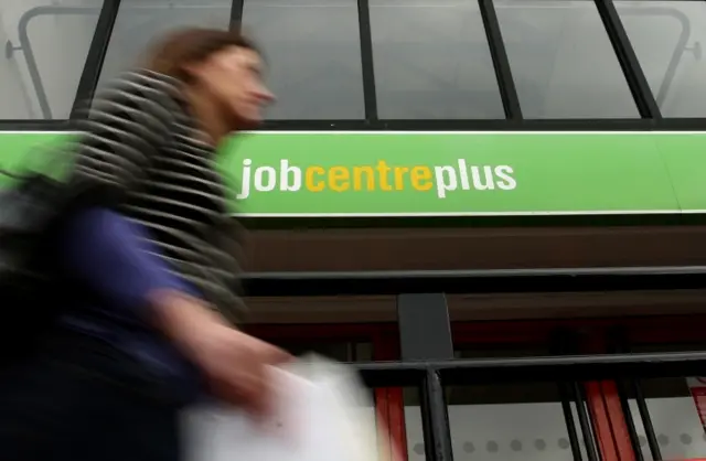 Woman walking past a Job Centre Plus office