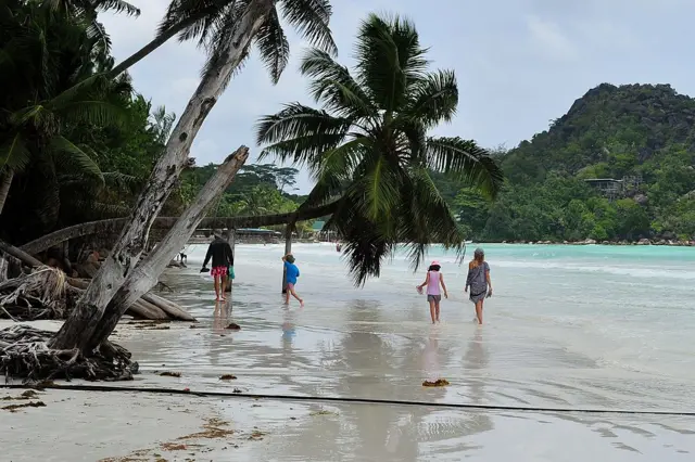 ourists walk on a beach on Praslin island on March 6, 2012.