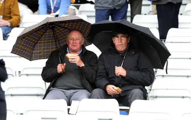 Fans eat snacks under an umbrella