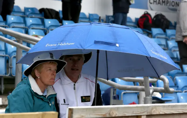 Fans shelter under an umbrella