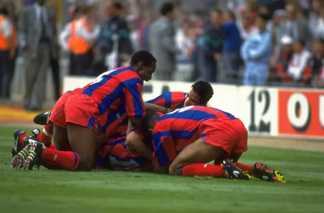 Ian Wright (hidden) is mobbed by his team-mates