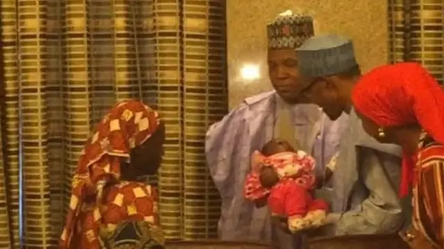 President Buhari cradles the baby with Amina standing by