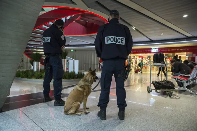 French officers of the Police aux Frontieres (PAF - Borders Police) with a dog stand guard at the Charles de Gaule airport near Paris