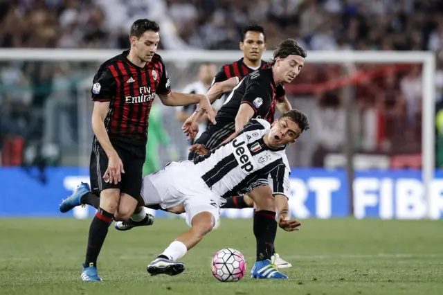 Juventus" Paulo Dybala (front) contrastated by Milan"s Mattia De Sciglio and Riccardo Montolivo (R)