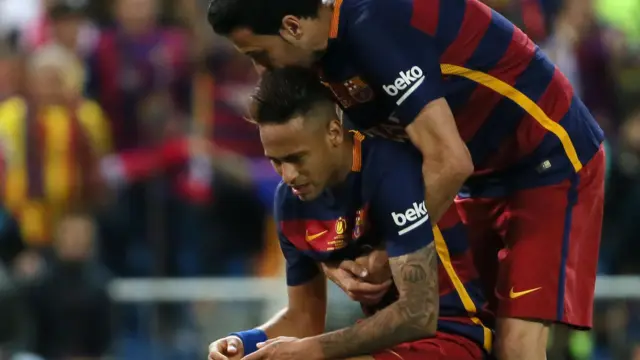 Neymar is helped up by Sergio Busquets