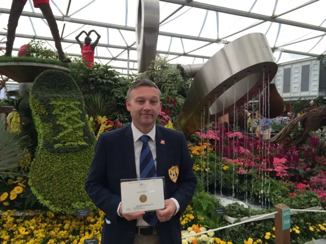 Head of Parks for Birmingham City Council, Darren Share MBE, with the award in front of the display