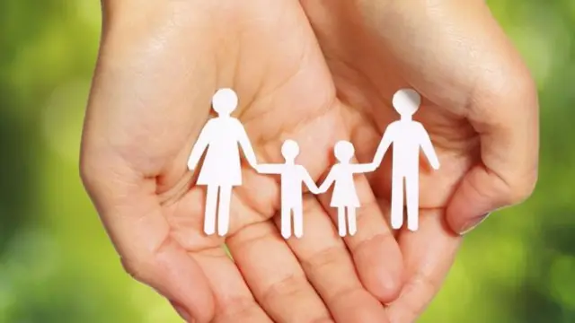 Hands cupped holding paper cut out of a family