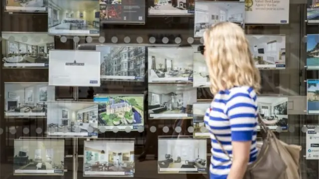 Woman passing estate agent window