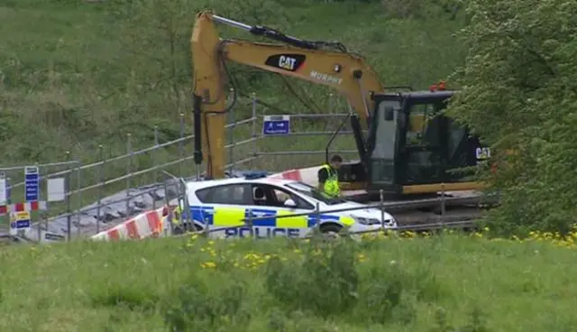 police car parked by digger on construction site