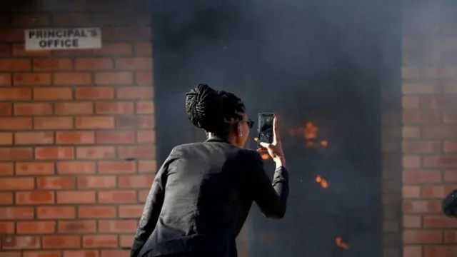 Woman taking a picture of a burning school