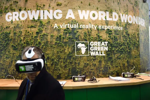 A man watches a movie with 3D glasses about the Great Green Wall in Africa at the Chad stand during the COP21