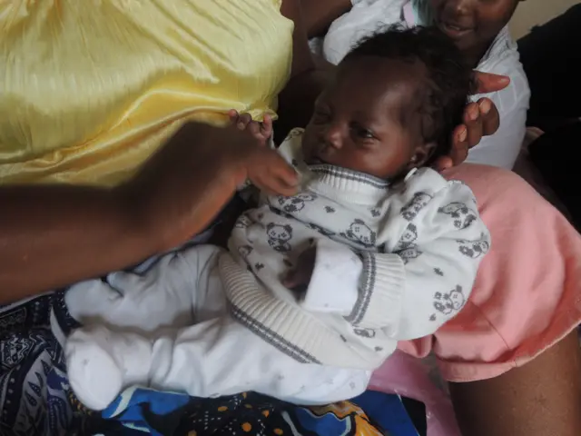 Baby Joy gets her pullover buttoned up