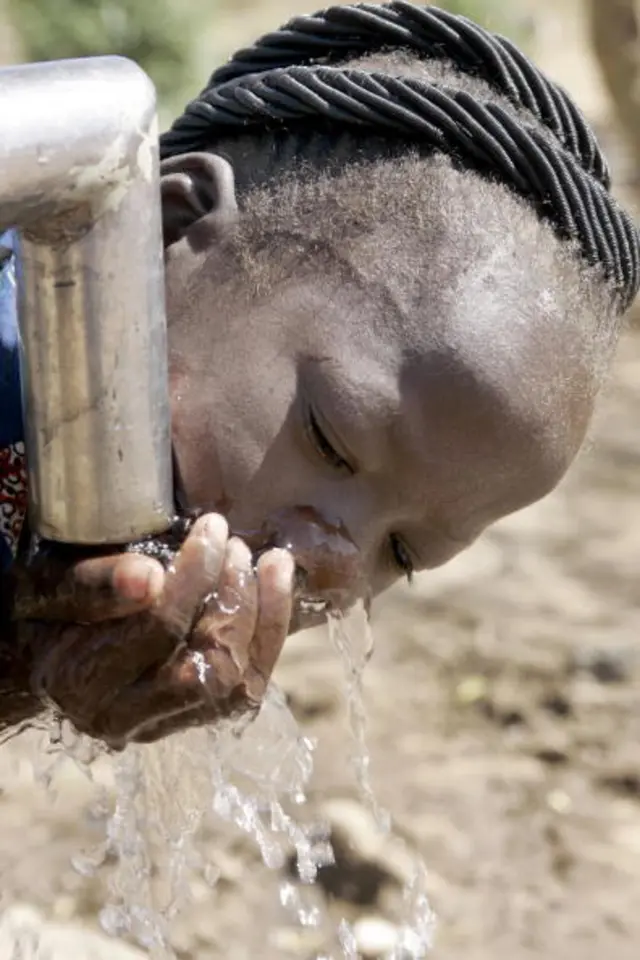 Person drinking water from an outside tap