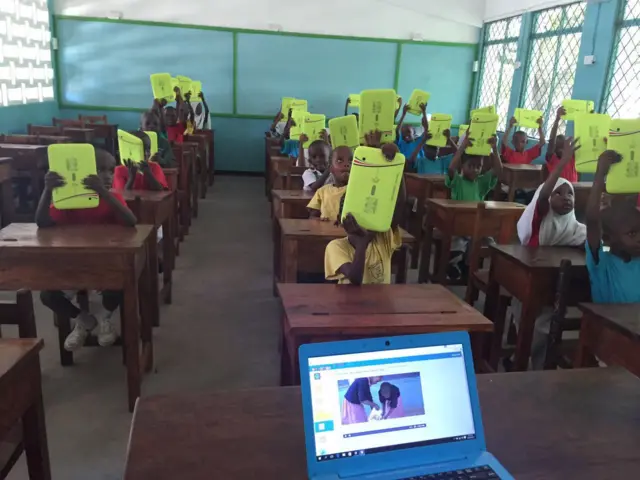 Class with students holding up tablets