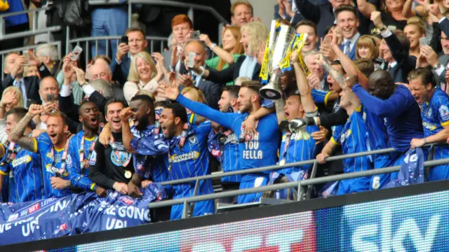 AFC Wimbledon players raise the play off final trophy