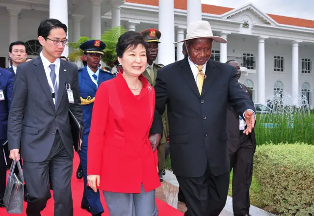 South Korea's President Park Geun-Hye (C) walks, accompanied by Uganda's President Yoweri Museveni (R), as they arrive for the inspection of a guard of honour of the Uganda People's Defence Force (UPDF), at State House in Entebbe, on May 29, 2016.