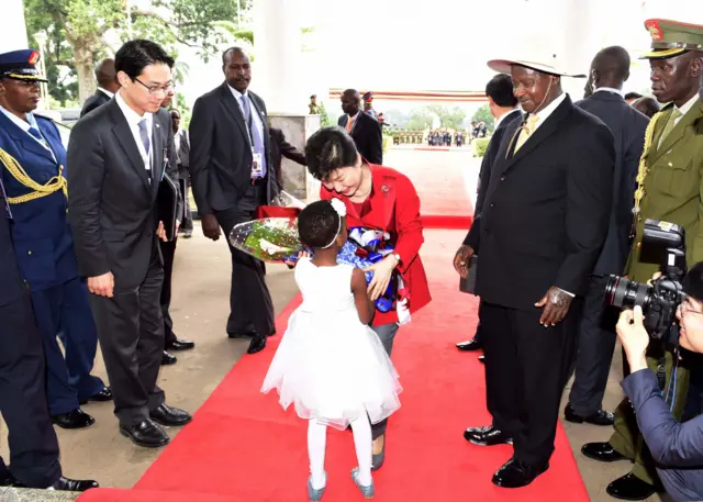 South Korea's President Park Geun-Hye (C) receives flowers from a five year-old girl next to Uganda's President Yoweri Museveni (R) before their meeting at State House in Entebbe, on May 29, 2016.