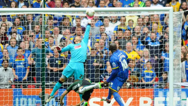 Adebayo Akinfenwa sees his shot saved by goalkeeper Luke McCormick