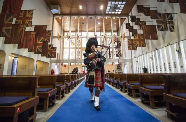 Piper Lance Sergeant John Mitchell plays during a procession to lay a set of 100-year-old bagpipes at The Guards Chapel in Wellington Barracks