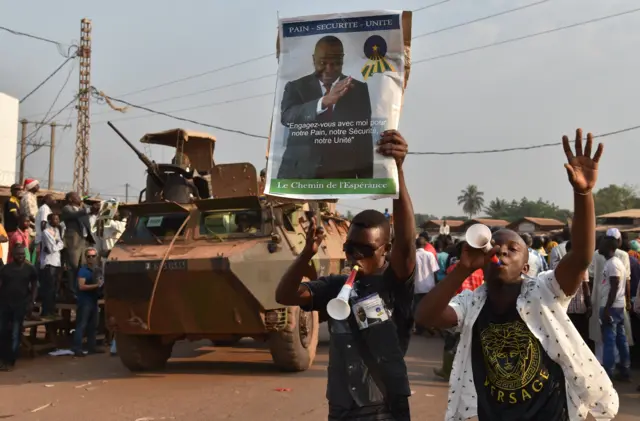 French soldiers of the Sangaris operation, the military intervention in Central African Republic, patrol in the PK5 Muslim district in Bangui on december 23, 2015 as supporters of Central African presidential candidate Karim Meckassoua hold electoral posters, during a campaign meeting.