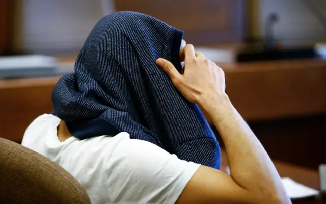 A 26-year-old Algerian who faces charges of assaults on woman during New Year"s Eve celebrations in Cologne, covers his head at a regional court in Cologne, western Germany, May 6, 2016.