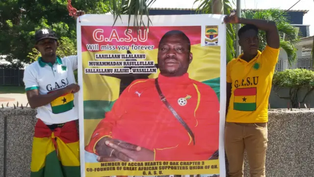 Two fans holding a memorial banner