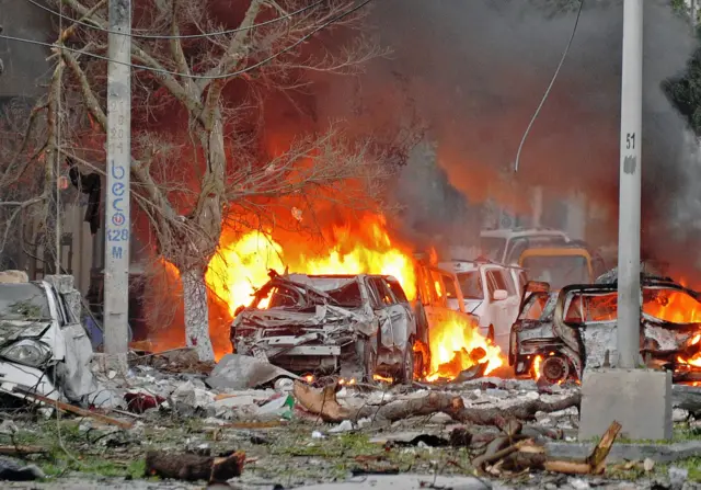 Wrecked cars burn at the scene of a terror attack at the Ambassador Hotel, after a car bomb exploded on June 1, 2016 at a top Mogadishu hotel that houses several MPs, killing several people, and followed by a gun battle.